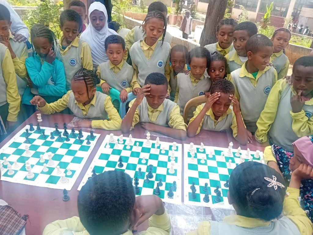 Students playing chess on wooden classroom tables, Ethiopia